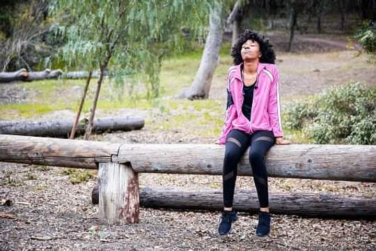 woman sitting on log in woods